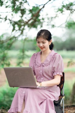 Güzel kız parktaki dizüstü bilgisayarı kullanıyor.