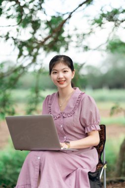 Güzel kız parktaki dizüstü bilgisayarı kullanıyor.