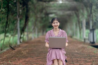 Güzel kız parktaki dizüstü bilgisayarı kullanıyor.