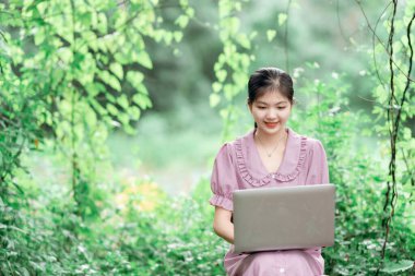 Güzel kız parktaki dizüstü bilgisayarı kullanıyor.