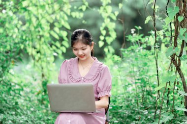 Güzel kız parktaki dizüstü bilgisayarı kullanıyor.