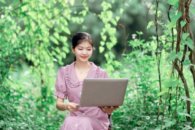 Güzel kız parktaki dizüstü bilgisayarı kullanıyor.