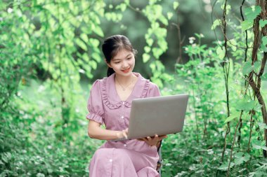 Güzel kız parktaki dizüstü bilgisayarı kullanıyor.