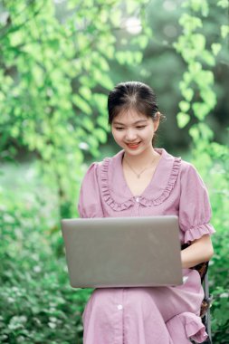 Güzel kız parktaki dizüstü bilgisayarı kullanıyor.