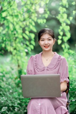 Güzel kız parktaki dizüstü bilgisayarı kullanıyor.