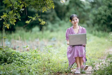Güzel kız parktaki dizüstü bilgisayarı kullanıyor.