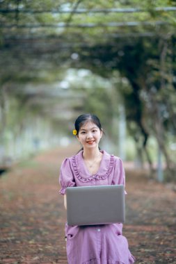 Güzel kız parktaki dizüstü bilgisayarı kullanıyor.