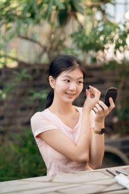 Asyalı kızlar avluda makyaj yapıyor.