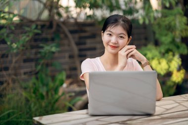 Kız bahçede dizüstü bilgisayar kullanıyor.