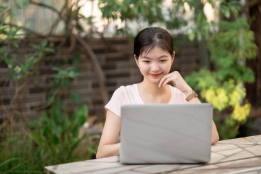 Kız bahçede dizüstü bilgisayar kullanıyor.