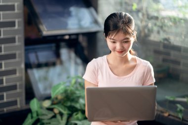 Kız bahçede dizüstü bilgisayar kullanıyor.