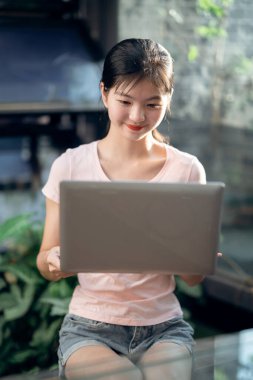 Kız bahçede dizüstü bilgisayar kullanıyor.