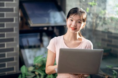 Kız bahçede dizüstü bilgisayar kullanıyor.