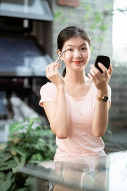 Asyalı kızlar avluda makyaj yapıyor.