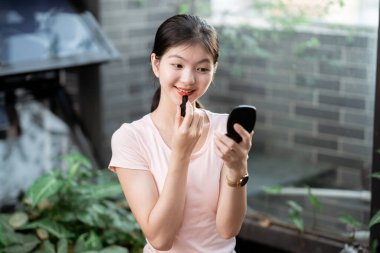 Asyalı kızlar avluda makyaj yapıyor.