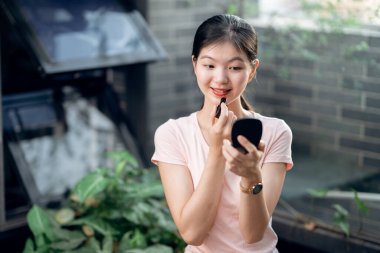 Asyalı kızlar avluda makyaj yapıyor.