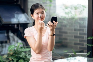 Asyalı kızlar avluda makyaj yapıyor.