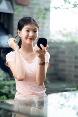 Asyalı kızlar avluda makyaj yapıyor.