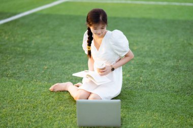 Üniversite öğrencileri futbol sahalarında dizüstü bilgisayar kullanıyorlar