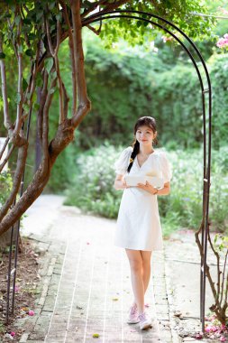 Bayan üniversite öğrencileri parkta kitap okurlar.