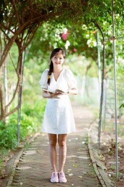 Bayan üniversite öğrencileri parkta kitap okurlar.