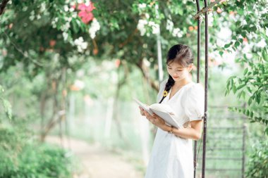 Bayan üniversite öğrencileri parkta kitap okurlar.