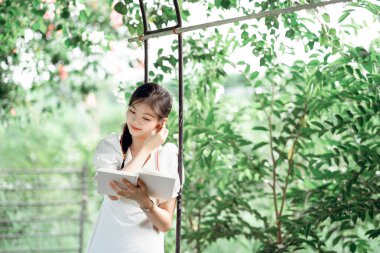 Bayan üniversite öğrencileri parkta kitap okurlar.