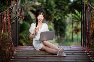 Bayan üniversite öğrencileri kampüste dizüstü bilgisayar kullanıyorlar.