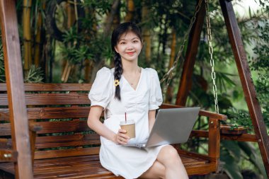 Bayan üniversite öğrencileri kampüste dizüstü bilgisayar kullanıyorlar.