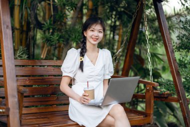 Bayan üniversite öğrencileri kampüste dizüstü bilgisayar kullanıyorlar.