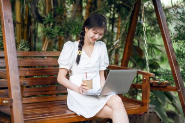 Bayan üniversite öğrencileri kampüste dizüstü bilgisayar kullanıyorlar.