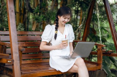 Bayan üniversite öğrencileri kampüste dizüstü bilgisayar kullanıyorlar.