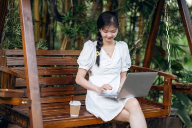 Bayan üniversite öğrencileri kampüste dizüstü bilgisayar kullanıyorlar.