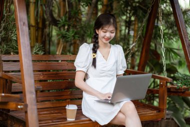 Bayan üniversite öğrencileri kampüste dizüstü bilgisayar kullanıyorlar.