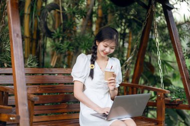 Bayan üniversite öğrencileri kampüste dizüstü bilgisayar kullanıyorlar.