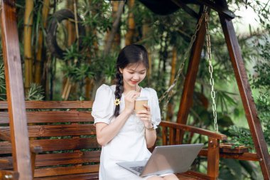 Bayan üniversite öğrencileri kampüste dizüstü bilgisayar kullanıyorlar.