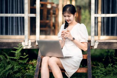 Bayan üniversite öğrencileri kampüste dizüstü bilgisayar kullanıyorlar.