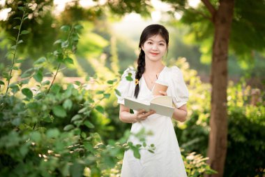 Bayan üniversite öğrencileri parkta kitap okurlar.