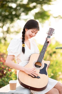 Kız parkta gitar tıngırdatıyordu.