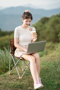 Kız çimlerde dizüstü bilgisayar kullanıyor.