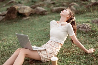 Kız çimlerde dizüstü bilgisayar kullanıyor.