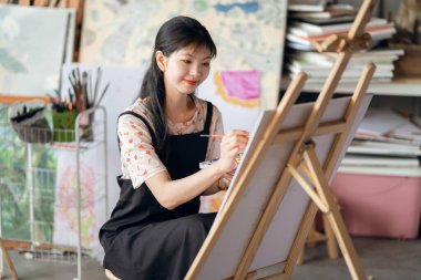 Kız stüdyoda resim çiziyor.