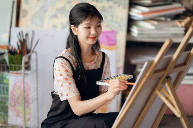 Kız stüdyoda resim çiziyor.