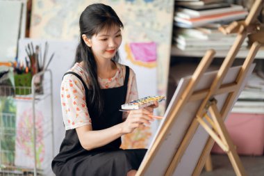 Kız stüdyoda resim çiziyor.