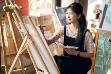 Kız stüdyoda resim çiziyor.