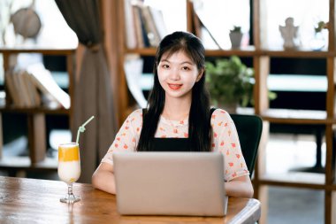 Kız kahve odasındaki dizüstü bilgisayarı kullanıyor.