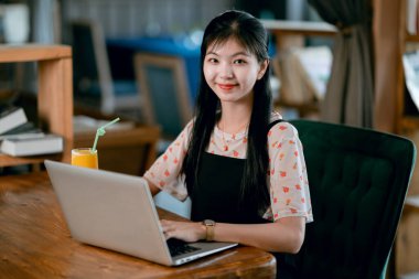 Kız kahve odasındaki dizüstü bilgisayarı kullanıyor.