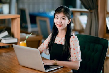 Kız kahve odasındaki dizüstü bilgisayarı kullanıyor.