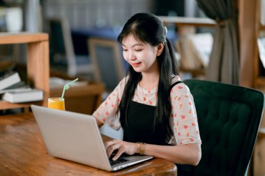 Kız kahve odasındaki dizüstü bilgisayarı kullanıyor.