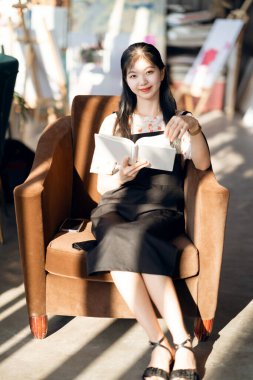 Kız kahve dükkanında okuyor.